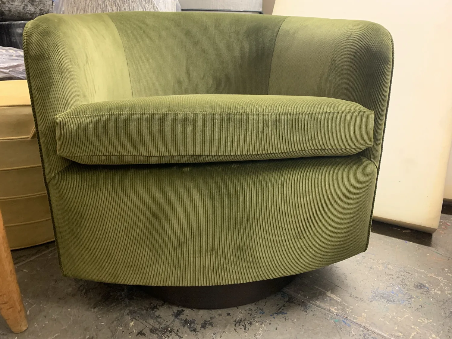 A swivel club chair upholstered in olive ribbed velvet, finished in the shop