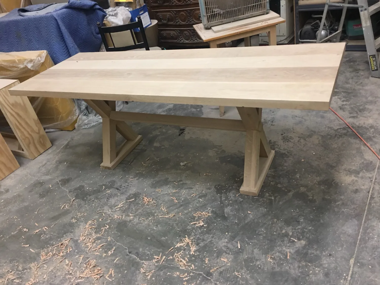 A solid white oak dining table on the shop floor, fresh from milling with shavings underneath