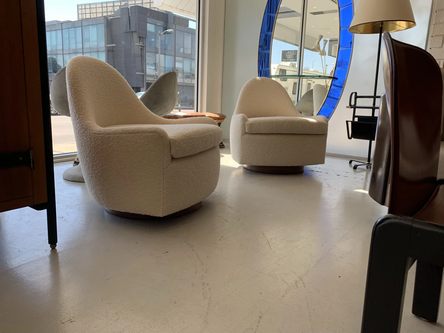 A pair of bouclé lounge chairs on swivel bases, finished and staged in the showroom